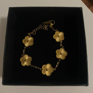 Klöver armband - Snyggt armband i guldtonad rostfritt stål med fem blommor som länkar. Blommorna har en räfflad yta och sitter på en tunn kedja med justerbar längd. Oanvänd & ask ingår ej.                                                     Säljer hela setet med örhängen, halsband & armband  i en annan anons ‼️
