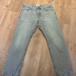 Grå raka jeans 32/30 - Snygga grå jeans från Jack&Jones i rak modell. Klassisk femficksdesign, normalhög midja och diskret tvättad look. Perfekta för dig som gillar en clean och stilren vibe. Jeansen är i 100% bomull och har Jack&Jones ikoniska bakfickor.
