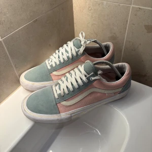 Vans Old Skool pastell sneakers - Säljer ett par Vans Old Skool sneakers i snygga pastellfärger. Skorna har ljusgrön mocka på tå och plös, rosa canvas på sidorna och vit vågig detalj. Klassisk vit sula och snörning. Perfekta för dig som gillar streetstyle och vill sticka ut lite extra.