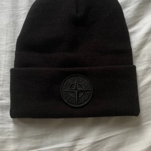 Svart Mössa Stone Island - Hej!  Säljer en svart mössa från Stone Island. Den är väldigt varm och kommer hålla ditt huvud varmt under vintern! Använde den förra vintern och den var jätteskön!  Vill du veta något mer eller vill ha fler bilder så är det bara att skriva! Priset är såklart inte hugget i sten!