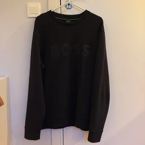 Boss Rhinestone Sweatshirt - Säljer en svart sweatshirt från BOSS i storlek M. BOSS-loggan är i rhinestone framtill. Sparsamt använd sen jag köpte den för något år sedan på thernlunds.