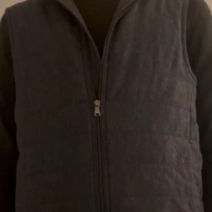 Väst från Oscar Jacobson - Snygg mörkgrå dunväst från Oscar Jacobson med quiltad design och hög krage. Använd väldigt lite. Absolut toppskick. Nypris 2900.