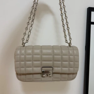 Beige quiltad axelväska Michael Kors - Snygg beige axelväska från Michael Kors med quiltad design och silverfärgad kedja. Köpt för 3500, använt 2-3 gånger. 
