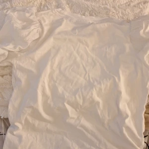 Vit blus med puffärmar  - Säljer en vit blus med puffiga korta ärmar och rund hals. Blusen är gjord i mjuk bomull och har en loose passform som ger en chill vibe. Perfekt för dig som gillar stilrena och enkla plagg med en twist på ärmarna.