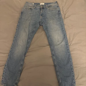 Blå tapered jeans från Jack & Jones - Snygga blå jeans från Jack & Jones i modellen Tapered/Mike. Klassisk femficksdesign med normal passform och avsmalnande ben. Jeansen är tillverkade i slitstarkt bomullsmaterial och har en cool tvättad look med ljusare partier. Priset är inte hugget i sten kan gå ner i pris vid snabbaffär! 