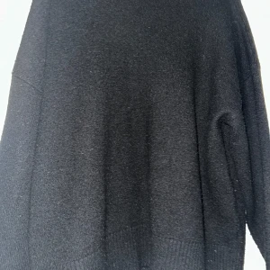 Svart stickad tröja  - En svart stickad tröja med lång ärm och ribbade muddar vid ärmslut och nederkant. Tröjan har en loose passform och är perfekt för att hålla sig varm under kyliga dagar. Enkel och stilren design som funkar till många olika outfits.