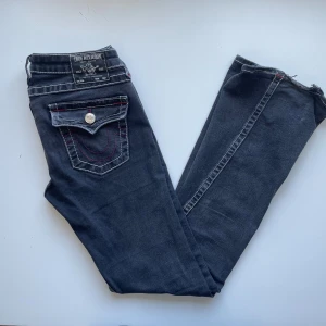 True Religion jeans - Svarta jeans från True Religion med vita och röda stygn. Joey Low Rise Flare i storlek 26. Använda men har inga andra deffekter än att de är lite slitna längst ner. Skriv om ni har frågor!!🖤