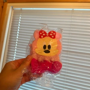 Minnie Mouse Pop It väska  - Sött Minnie Mouse med pop it-funktion, rosa och röd design. Väskan är nytt och fortfarande i plastförpackning, utan synligt slitage eller defekter. Perfekt för dig som vill skydda dina ägodelar och samtidigt ha en rolig stressleksak. Både för barn och vuxna. Perfekt som present i för jul 🎄 eller födelsedagar 🎂  väskan kommer så som på bild och rem till väskan tillkommer också som finns inne i väskan och kan hängas på var sin sida av väskan.