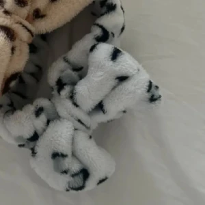 Fluffigt hårband med leopardmönster - Supermjukt och fluffigt hårband i beige och vitt med coolt leopardmönster. Perfekt accessoar för att hålla håret borta när du sminkar dig eller bara vill ha en söt detalj. Tillverkat i gosigt syntetmaterial som känns skönt mot huden.