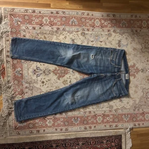 Blå jeans från Tiger of Sweden - Snygga blå jeans från Tiger of Sweden med slitningar och en liten reva på låret. Klassisk femficksmodell med raka ben och normal passform. Jeansen har en cool tvättad look och är tillverkade i bomull. Perfekta för dig som gillar en avslappnad stil.