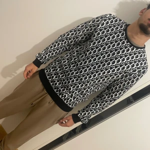 Svartvit Björn Borg sweatshirt - Säljer en svartvit sweatshirt från Björn Borg med all-over logomönster. Tröjan har rund hals, svarta muddar vid ärmslut och midja samt lång ärm. Perfekt för dig som gillar streetstyle och vill sticka ut med en cool printad look.