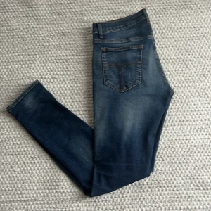 Mörkblå slim jeans från tiger of Sweden  - Tjena! Säljer ett par snygga mörkblå jeans från TOS med snygga och diskreta slitningar. Modellen är slim, Jeansen är tillverkade i mjukt denim med stretch för extra komfort.                                                                   Hör av er i dm vid frågor eller prisförslag! 
