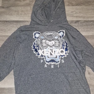 Kenzo hoodie storlek XS passar för folk mellan 168-175 - Snygg grå hoodie från Kenzo i storlek XS med ikoniskt broderat tigerhuvud och Kenzo Paris-logga framtill. Tröjan har huva med snörning och är långärmad. Perfekt för dig som vill sticka ut med en streetstyle-look.
