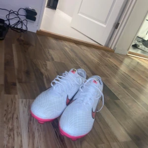 Fotbollskor  - Säljer ett par Nike Mercurial Superfly i elegant vitt med rosa och svarta detaljer. Skorna är i mycket gott skick och endast sparsamt använda. Den lätta och slitstarka designen ger optimal komfort, perfekt bollkänsla och maximalt grepp på planen – utvecklade för spelare som värdesätter snabbhet och precision. Inspirerande detalj med texten “When you believe in yourself” längs sidan. Storlek: 43 Pris: 1850 Priset är inte suttet i sten