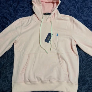 Ljusrosa hoodie från Polo Ralph Lauren - Ljusrosa hoodie från Polo Ralph Lauren. Lite stor i storleken och säljer därför den. Storlek M men passar väl storlek L
