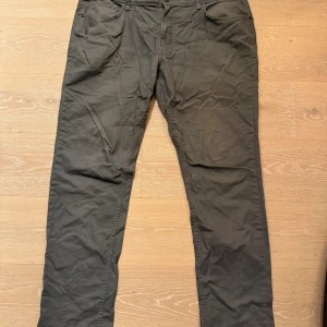 Grå slim chinos från Angelo Litrico - Snygga grå chinos från Angelo Litrico med slim leg-passform. Klassisk femficksmodell med bälteshällor och knappgylf. Perfekta för dig som gillar en stilren look med smalare ben. Tillverkade i mjuk bomull för skön känsla hela dagen.