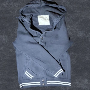 Marinblå hoodiejacka Abercrombie - Fet marinblå hoodiejacka från Abercrombie. Skönt plagg till nuvarande säsong. Asfet luva i dun. Passar dig mellan 183-190 cm. Hör av dig vid frågor :) Priset kan diskuteras