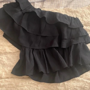 Kort volang topp från Vero Moda - Supersnygg marinblå volang från Vero Moda med flera lager volanger och oneshoulder-design. Croppad passform som ger en cool och trendig look. Perfekt att styla med jeans eller kjol för en extra touch. Materialet är lätt och känns skönt mot huden. Köpt på Vinted