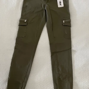 Olivgröna cargopants från FB Sister - Olivgröna cargopants från FB Sister med dragkedjor vid benslut och stora fickor på sidorna. Aldrig använda. Endast testade.