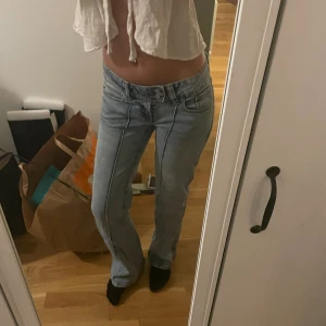 lowwaist Ljusblå jeans   - Säljer ett par ljusblå jeans lågmidjade. Jeansen har klassisk femficksdesign, synliga sömmar framtill och stängs med dubbla knappar och dragkedja. Perfekta för en chill och stilren look.