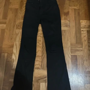 Svarta bootcut jeans från Denim 1953 - Svarta jeans från Denim 1953 i modellen Susan. Byxorna har bootcut passform och klassisk femficksdesign. Tillverkade i ett stretchigt bomullsmaterial som sitter snyggt och bekvämt. Perfekta för dig som gillar en tidlös look med lite utsvängda ben.