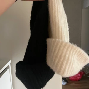 En Svart och en vit ribbstickad mössa - Glitter - Två ribbstickade mössor i klassisk modell, en svart och en vit. Båda har bred uppvikt kant och är stickade i mjukt material som känns skönt mot huden. Köpta förra året, helt oanvända 