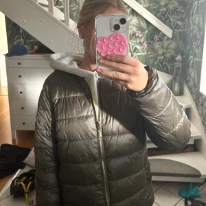 Mörkgrå pufferjacka med dragkedja - Säljer en stilren mörkgrå pufferjacka med horisontella quiltade sektioner och hel dragkedja framtill. Jackan har en klassisk, normal passform och är tillverkad i syntetmaterial som ger en lätt och skön känsla. Perfekt för kyliga dagar och enkel att matcha med din hoodie. Använd fåtal gånger. Köpt för 1200 