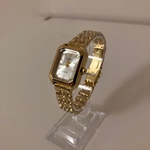 Guldfärgad XIMILI klocka med länkarmband - Snygg guldfärgad klocka från XIMILI med rektangulärt ur och länkarmband i metall. Urtavlan är vit med guldiga detaljer och minimalistisk design. Quartz-urverk och stilren look som lyfter din outfit.                            ✅Frakt inom 24 timmar 📦.                                                         ✅Nytt batteri 🔋.                                                                         