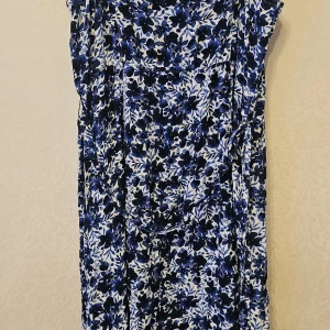 Blommig långklänning Holly & Whyte - Långklänning från Holly & Whyte by Lindex i blått och vitt med blommigt mönster. Klänningen är ärmlös, har knappar framtill och är tillverkad i ett lätt och luftigt material, perfekt för varma dagar. Snygg och flowy passform som ger en avslappnad look.