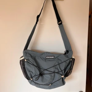 Blå axelväska från Iets frans… - Blå axelväska från urban outfitters. Använd 2-3 gånger, rymlig och får plats med mycket i de 2 stora facken. Finns innerfickor och ett ytterfack, och även 2 vattenflask hållare. 