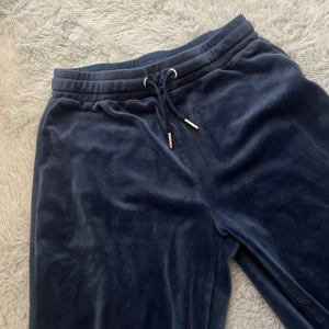 Mörkblå mjukisbyxor från Gina Tricot - Mysiga mörkblå mjukisbyxor från Gina Tricot i mjukt fleecematerial. Byxorna har resår i midjan med snörning och två bakfickor. Perfekta för chill eller häng hemma.