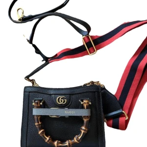 Gucci svart axelväska med bambuhandtag - Knappt använd. Snygg svart axelväska från Gucci i skinn med ikoniskt bambuhandtag och guldfärgade detaljer. Väskan har bred axelrem i rött och marinblått, samt GG-logga framtill. Finns en till axelrem i svart läder. Låda och dustbag finns. 