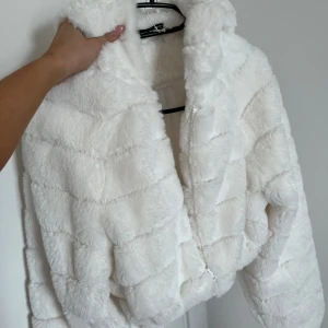 Vit pälsjacka  - Supermjuk och fluffig vit pälsjacka med dragkedja framtill. Jackan är croppad och har en bred krage som ger en cool och trendig look. Jätte mysig och skit snygg! Aldrig använd. Storlek 36.