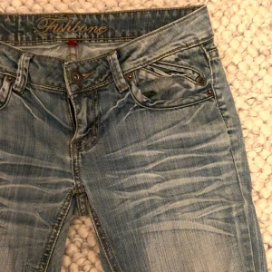Blå Fishbone jeans med dragkedjor - As coola ljusblå lågmidjade vintage jeans, finns ett hål (se sista bilden) men de syns inte alls och är väldigt lätt att laga❤️❤️ innerbenslängd: 85cm, midjan är en S