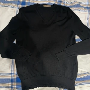 Svart v-neck pullover från Burberry - Svart v-neck pullover från Burberry Tröjan är stickad i mjukt merinoull och har långa ärmar med ribbade muddar och nederkant. Perfekt för dig som gillar klassisk stil med en lyxig touch. Orginal pris 1950kr, Säljer för 599kr!! Priset går att diskuteras!