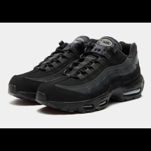 Nike Air Max 95 Triple Black - Nike Air Max 95 Triple Black sneakers med ikonisk vågig design, synliga Air-enheter i sulan och svart mesh samt skinnpaneler. Skorna har snörning och en chunky sula som ger en sportig vibe. Perfekta för dig som gillar streetwear och klassisk Nike-stil.