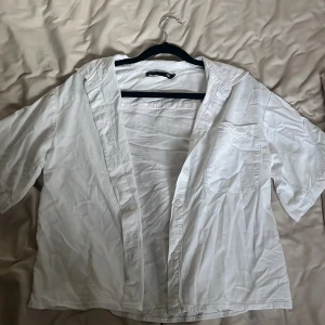 Vit kortärmad skjorta från 157 XS - Fräsch vit skjorta från 157 i storlek XS. Modellen har korta ärmar, klassisk krage och en bröstficka. Skjortan är tillverkad i mjuk bomull och har knappar framtill. Perfekt för dig som gillar enkel och clean stil.