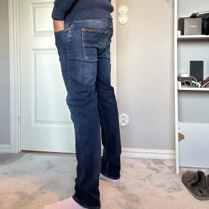 Blå jeans från Nudie Jeans grim Tim - Säljer ett par klassiska blå jeans från Nudie Jeans med snygga kontrastsömmar och broderad bakficka. Modellen är grim tim vilket är en rak modell. Jag bär storlek 33/32 och jag är 188cm. Jeansen är i riktigt bra skick. Nypris ligger på 1600kr. Hör av er vid funderingar;)
