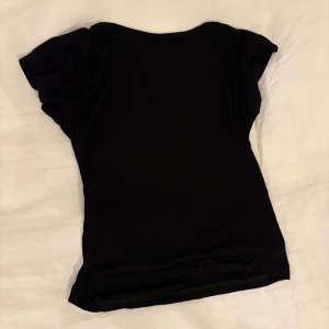 Svart kortärmad topp - Enkel svart topp med öppen rygg. Helt oanvänd.