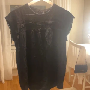 Svart blus  - Svart blus från Vero Moda i storlek S med rund hals och dekorativa bollar längs halsringning och ärmslut. Blusen har ett enkelt, rakt snitt och är ärmlös. Perfekt för dig som gillar stilrena och klassiska plagg med en twist. Hör gärna av er vid frågor eller funderingar! 💖