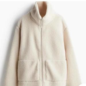 Beige teddyjacka med dragkedja - Mysig beige teddyjacka med hög krage och hel dragkedja framtill. Jackan har två stora fickor och är tillverkad i fluffigt teddy-material som håller dig varm, är i storlek L men sitter som en M. Köp av ett mindre pris om försäljningen går fort