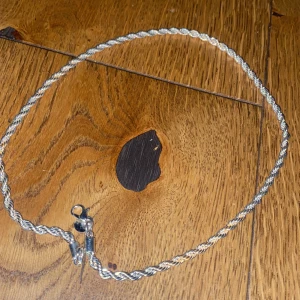 Tjockt tvinnat silverfärgat halsband - Säljer ett snyggt halsband med tvinnad kedja i silverfärg. Kedjan är ganska tjock och har en klassisk karbinhake. Perfekt för dig som gillar stilrena och tidlösa smycken med lite extra edge.
