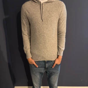 Ljusgrå hoodie  - Säljer denna snygga merinoull hoodien eftersom den börjar bli för kort på mig. Tröjan är använd men har inga Defekter och är fortfarande i bra skick. Köpt för 899. Mitt pris: 499kr. Hör av er vid frågor eller funderingar!