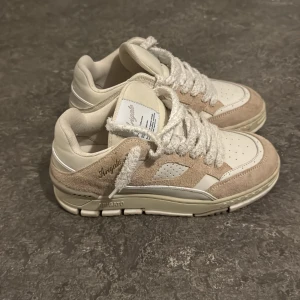 Axel Arigato sneakers beige/vit - Snygga sneakers från Axel Arigato i beige och vitt med coola detaljer i mocka och skinn. Skorna har chunky sula, breda snören och perforerade partier på tån. Perfekt för dig som gillar stilrena men trendiga sneakers. Vad använt de några gånger bara. Lite stor i storlek*