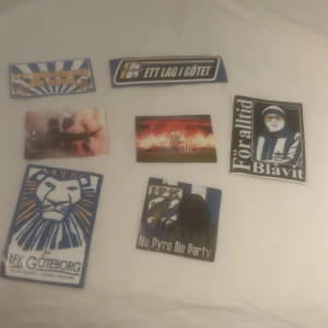 IFK Göteborg supporterklistermärken - Samling med sju klistermärken för IFK Göteborg-fans. Motiven inkluderar klubbens lejon, pyroteknik, slogans som 'Ett lag i Göte' och 'För alltid Blåvit'. Perfekt för dig som vill visa ditt stöd för Blåvitt på väskan, datorn eller skateboarden.