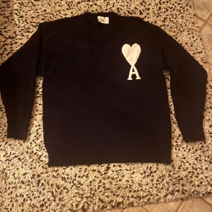  Ami Paris tröja - Blå stickad tröja från Ami Paris med vit hjärtlogga och bokstaven A på bröstet. Klassisk rund halsringning och långa ärmar. Perfekt för dig som gillar stilrena plagg med en twist. Gör skönt material!! Priset är ej hugget i sten. Aldrig använd,är för liten. Hör av er om ni undrar något☺️