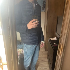 Mörkblå pufferjacka Tommy Hilfiger - Snygg mörkblå pufferjacka från tommy hillfiger. Perfekt för nu i höst eller vinter och har en stilren look. Den är ny det är inga defekter och den passar bra. Jag är 186 och passa bra. Orginal  priset är 2300, om du har frågor är det bara att skriva!