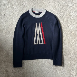 Moncler x Ami stickad tröja - Hej! Säljer denna stickade Moncler tröja i samarbete med Ami paris! Denna stickade tröjan är det perfekta valet för dig som vill hålla dig varm nu under hösten och vintern! Tröjan har varsina 3 metallöglor på underarmarna för ventilation! Kragen, sömmarna och designen representerar Ami och det tre kontrastfärgerna på tröjan representerar Moncler! Finns endast en liten pinhole som jag visar på bild 4 men syns inte vid användning. Varmt välkommen att skriva vid minsta intresse 🤗 mvh DC 🔹