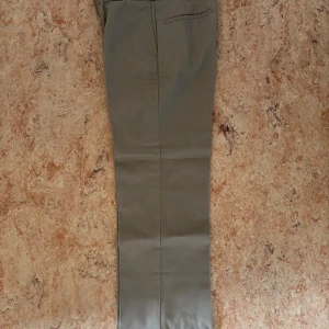 Beige Dickies 874 Original Fit byxor - Klassiska beige Dickies 874 Original Fit byxor med rak passform och diskret bakficka med dragkedja. Tillverkade i slitstarkt material som ger en clean och tidlös look. Perfekta för dig som gillar streetwear eller vill ha en enkel stilren vibe.