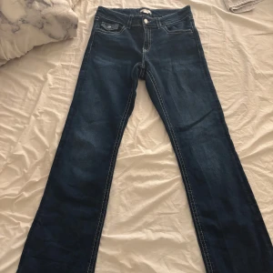 Chunky low flare jeans från Gina Tricot - Mörkblå chunky low flare jeans från Gina Tricot med kontrastsömmar och klassiska fickor fram och bak. Jeansen har låg midja och utsvängda ben för en trendig look. Perfekta för dig som gillar 70-talsvibbar och vill sticka ut.